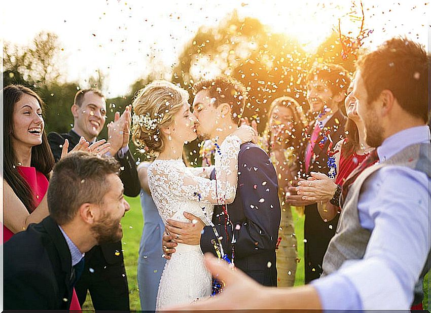 Bride and groom kissing at the wedding with groomsmen and family