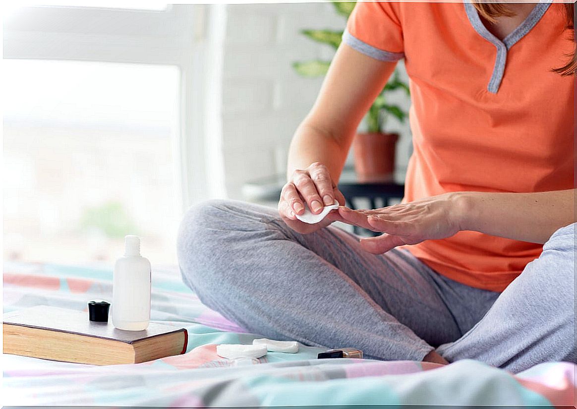 Woman paints her nails in bed.