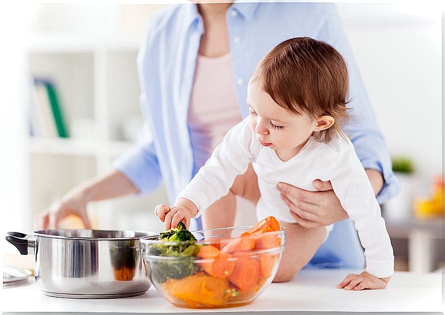 Mom with baby cooking vegetables